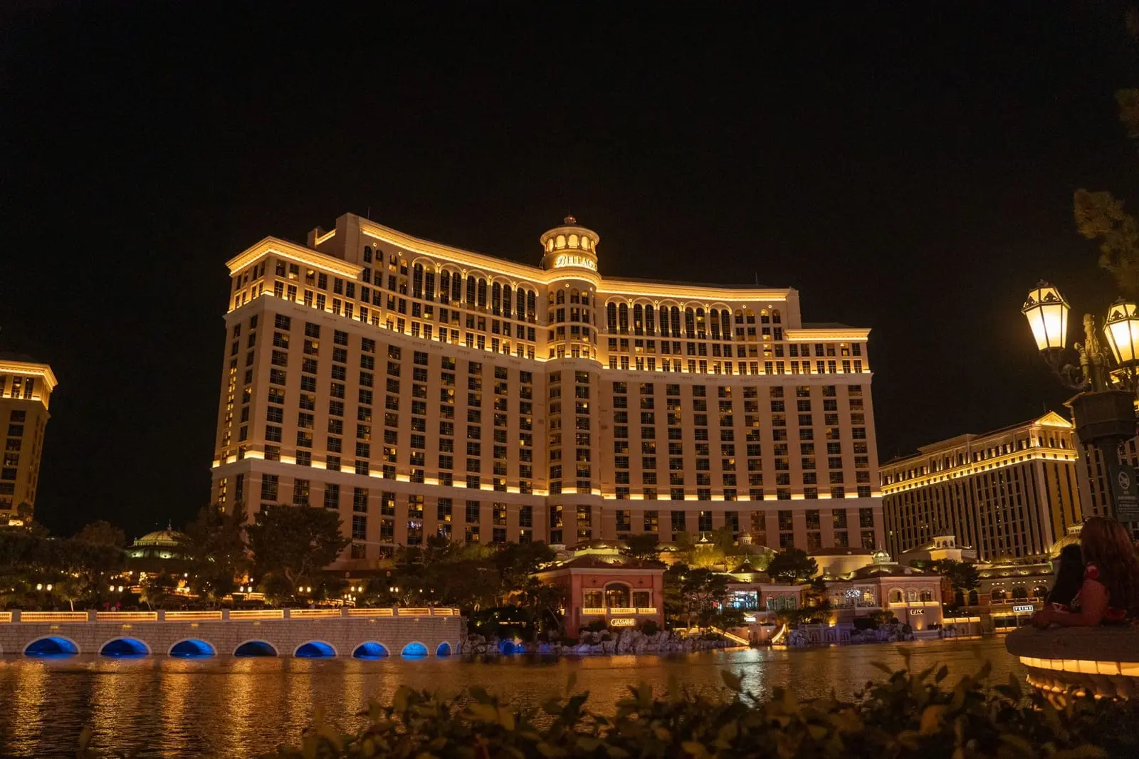 The Bellagio resort glowing gold at night across its lake.