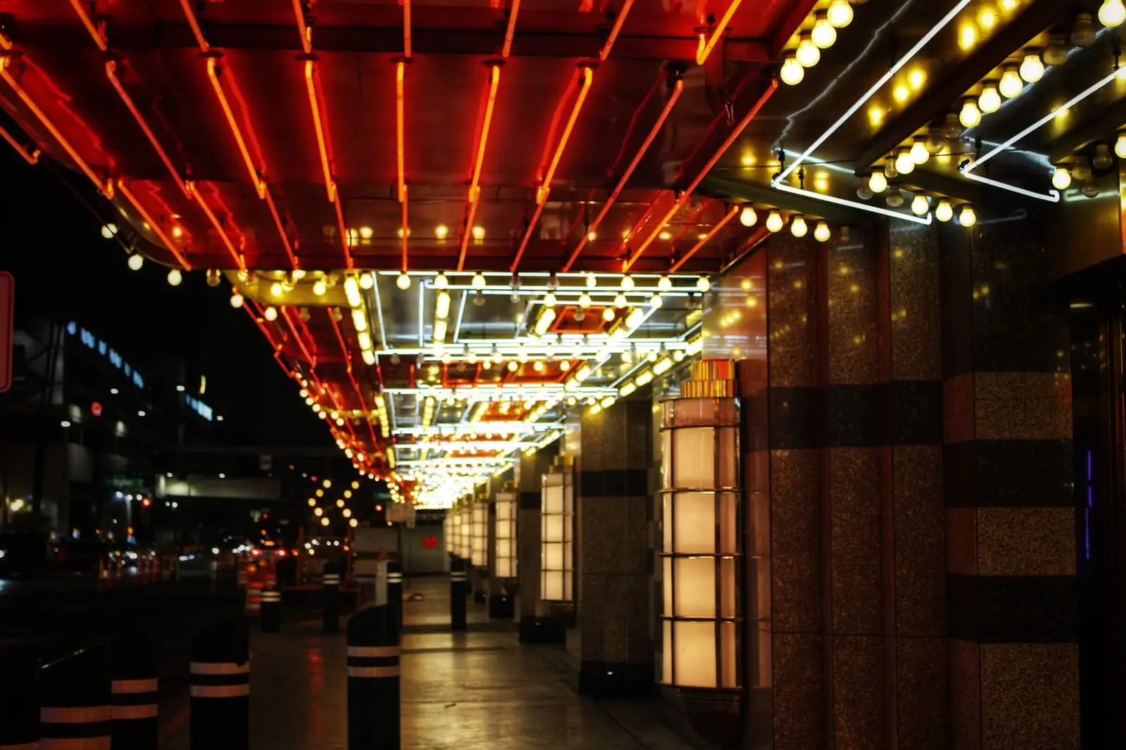 A covered casino walkway glowing with red and gold marquee lights at night.