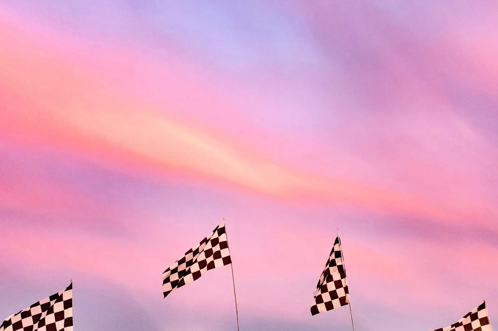 Chequered flags flying against a pink and purple sky.