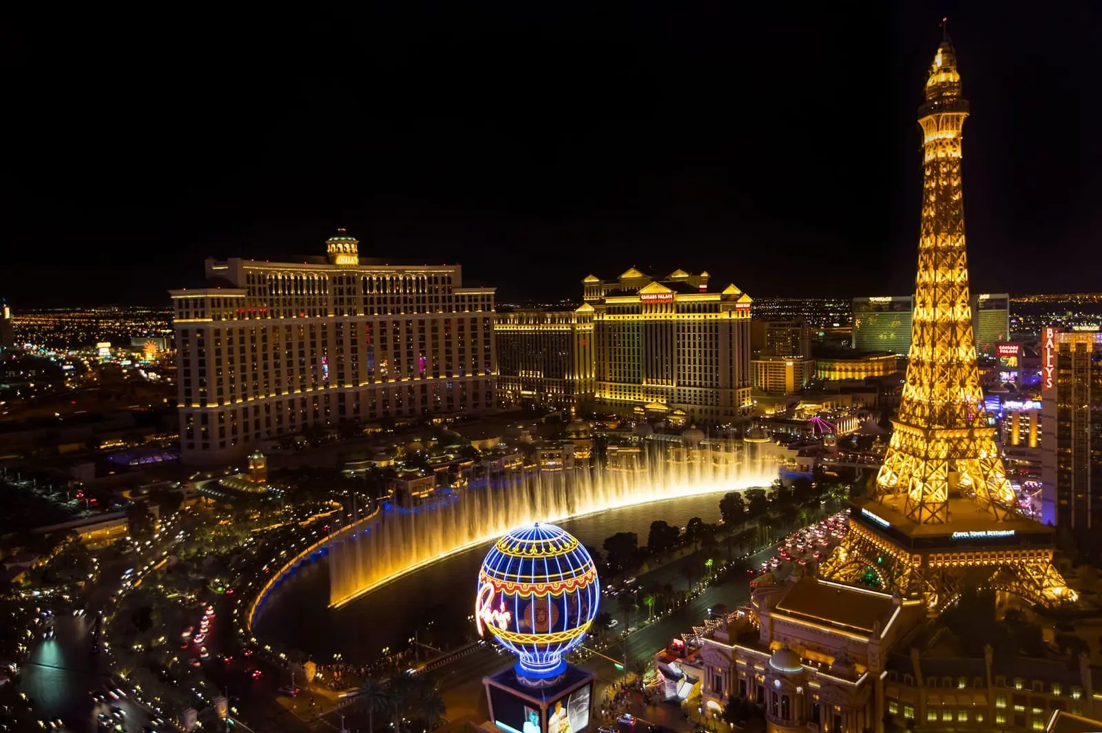 Aerial night view of the Paris Las Vegas Eiffel Tower and balloon sign beside the Bellagio fountains.