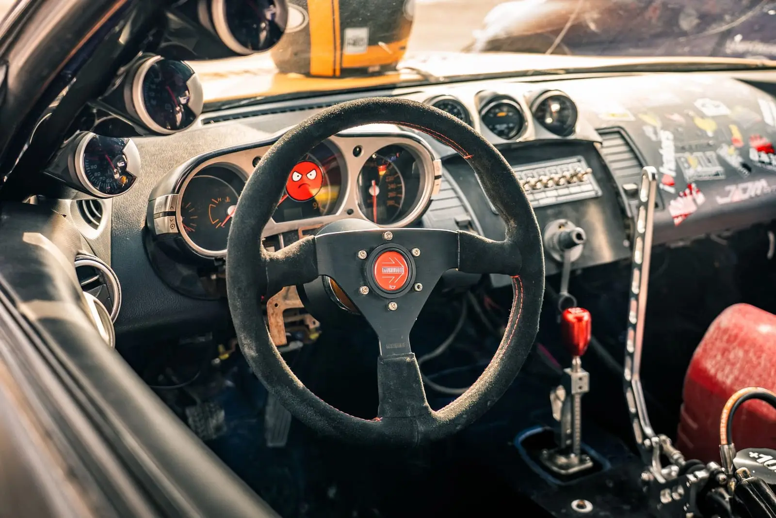 The stripped-out cockpit of a modified race car: wheel, gauges and roll cage.