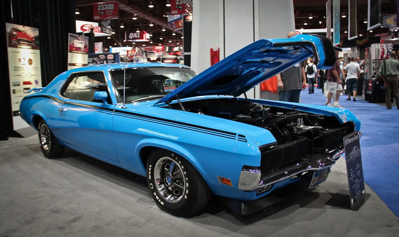 A blue classic muscle car with its hood up at the SEMA Show in Las Vegas.