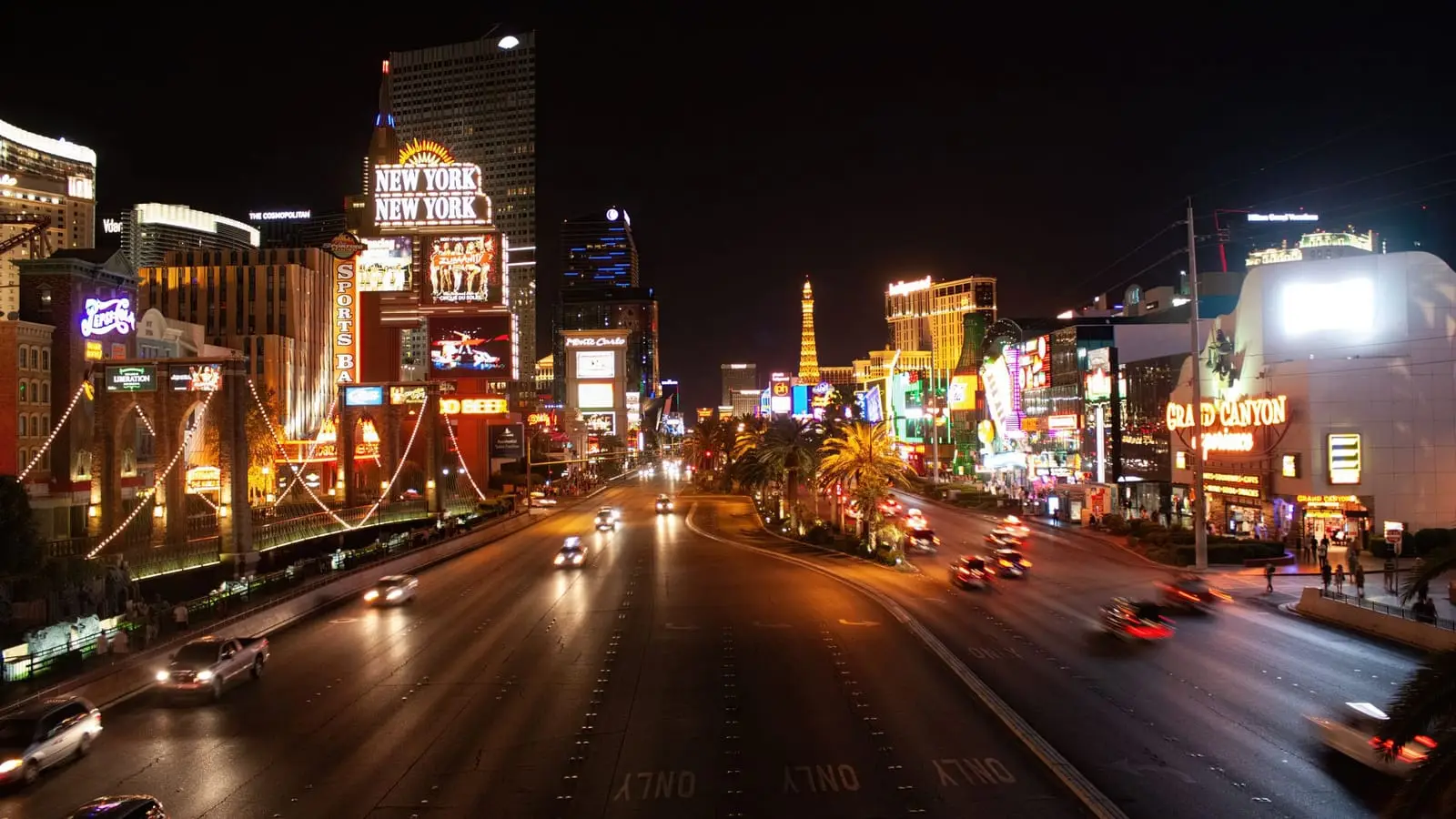 Las Vegas Boulevard at night, lined with casino signs and moving traffic.