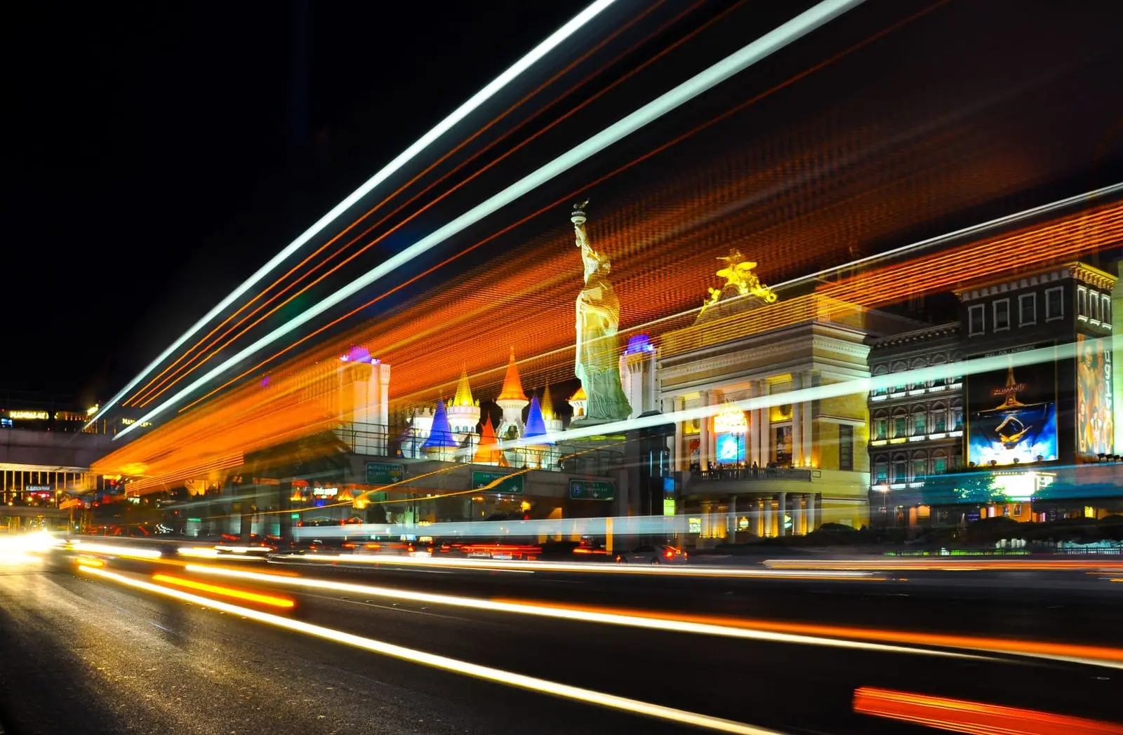 Motion-blurred light streaks rushing past Strip resorts at night.