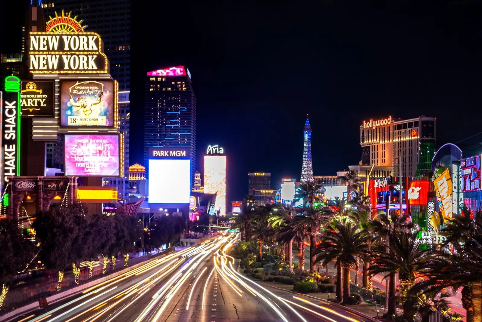 Traffic light trails sweep down Las Vegas Boulevard past New York-New York and the Strip's neon at night.