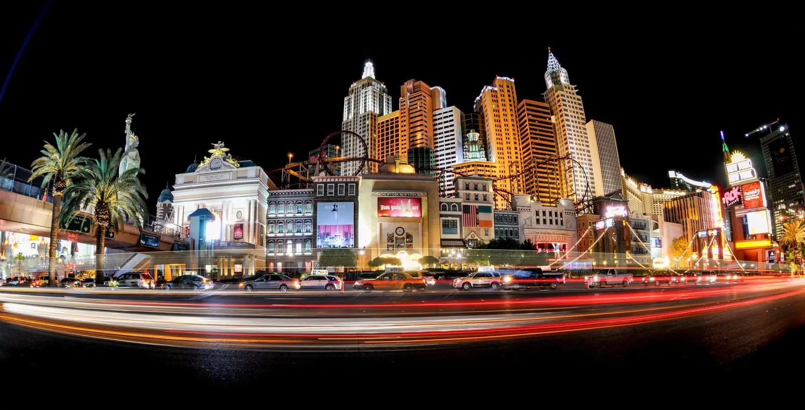 Long-exposure panorama of the Strip skyline with red and white traffic streaks.
