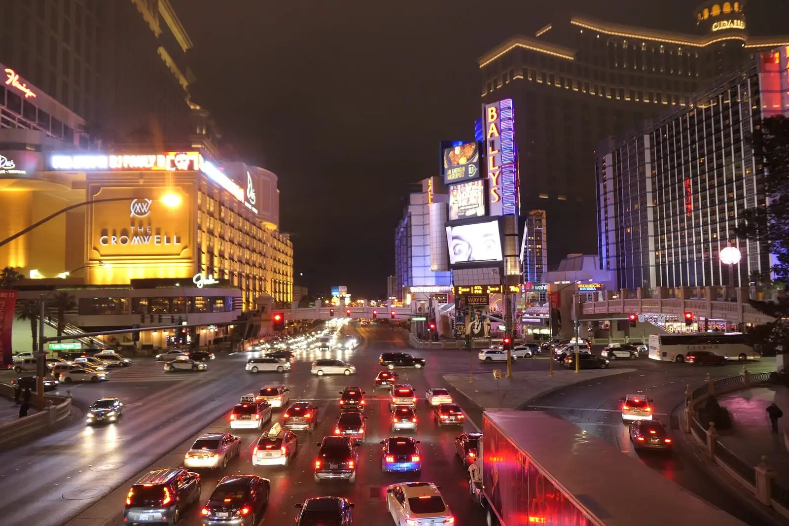 Heavy evening traffic on Las Vegas Boulevard between brightly lit resorts.