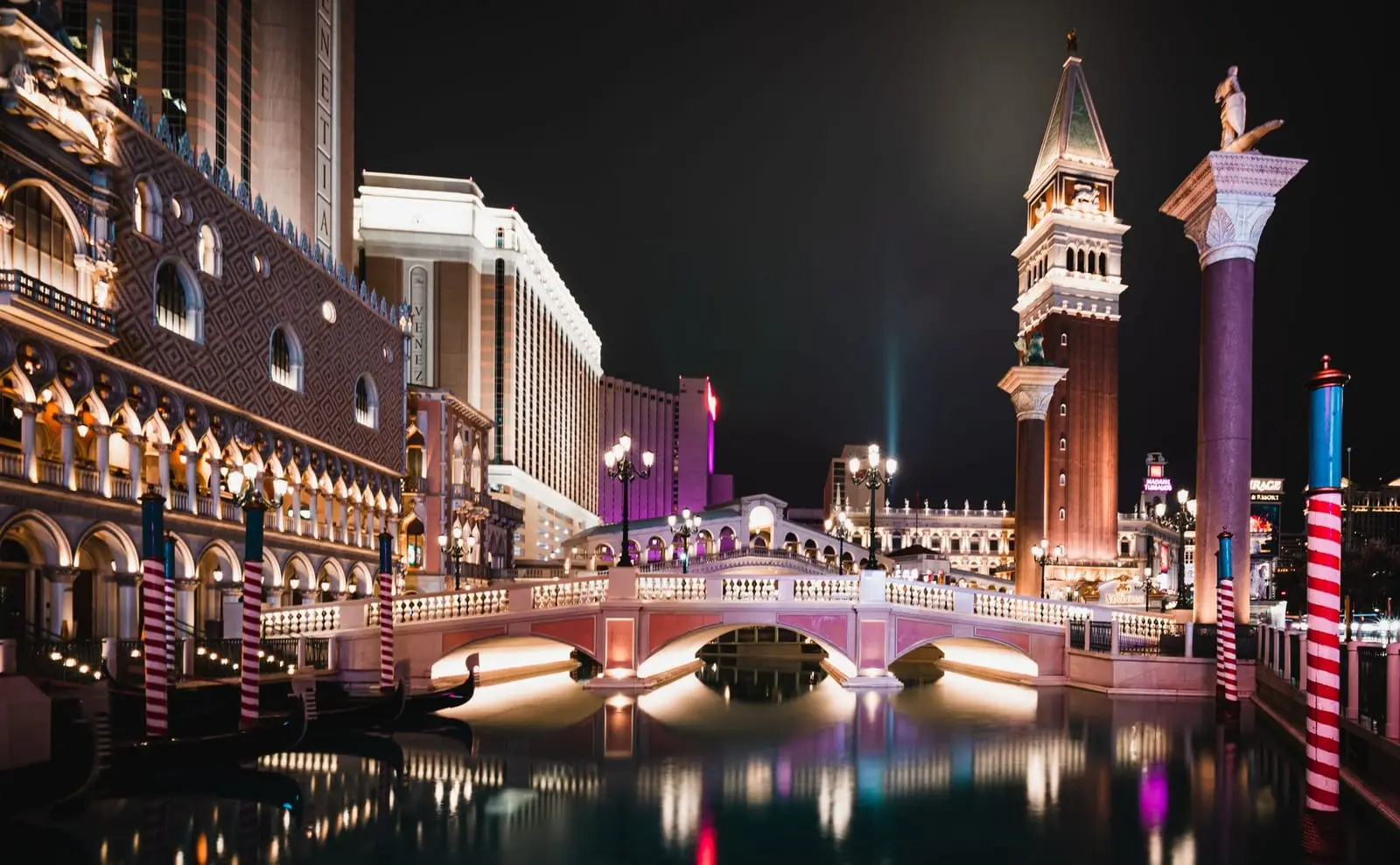 The Venetian's bridge, bell tower and canal lit up at night on the Strip.