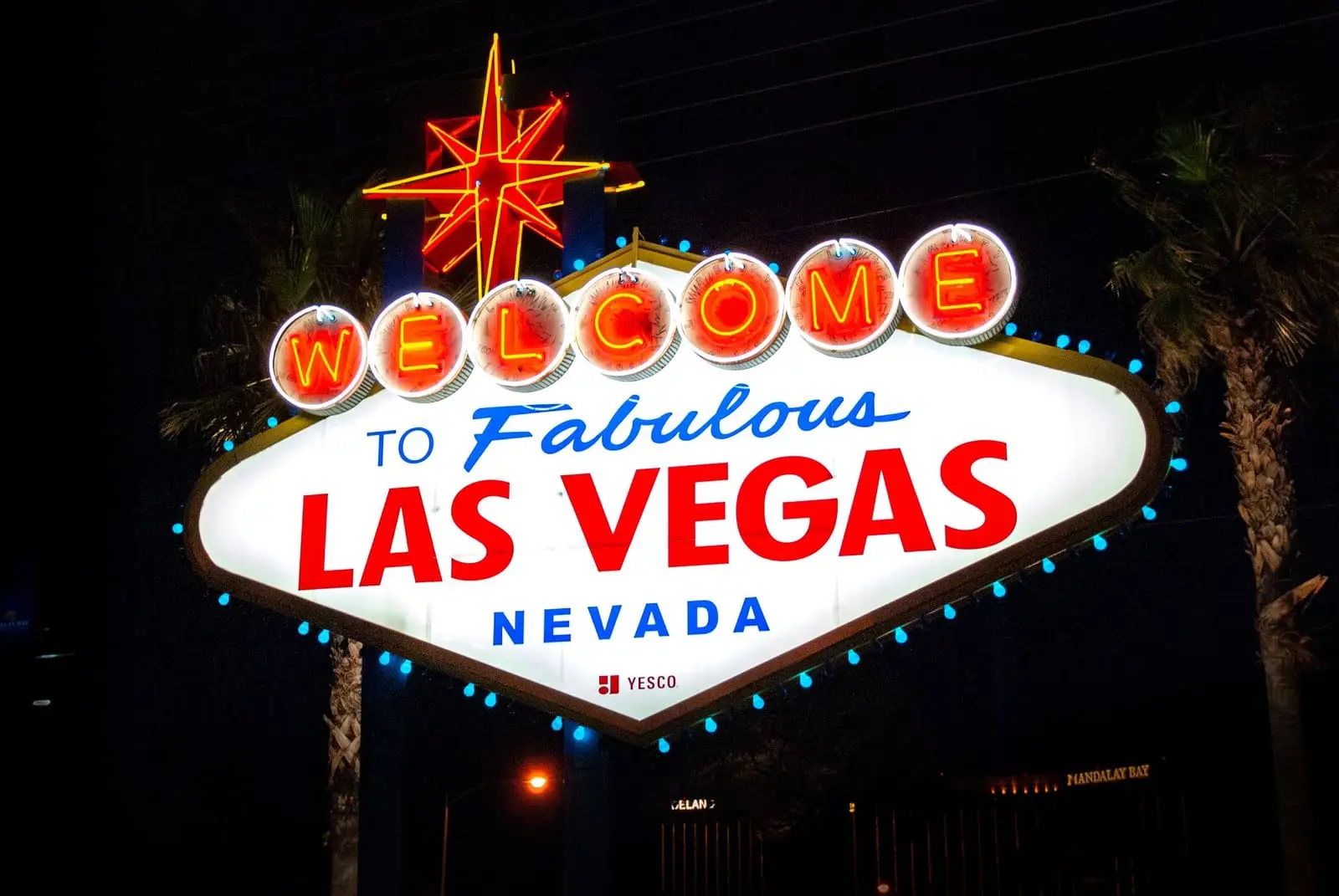 The Welcome to Fabulous Las Vegas sign lit up at night between palm trees.